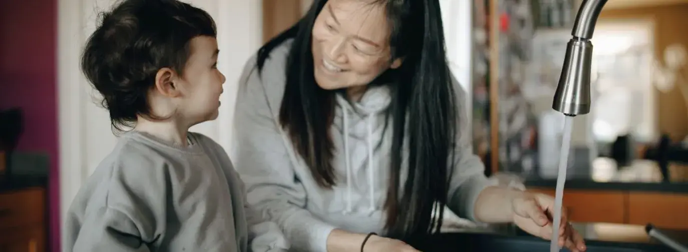 Asian mother and child washing strawberries in the kitchen